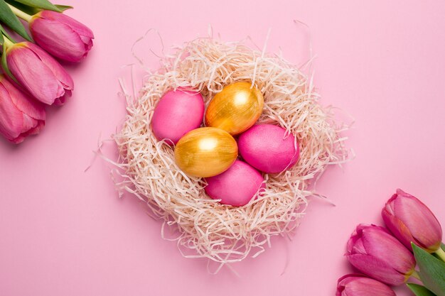 Easter pink and gold eggs with flowers on a pink surface