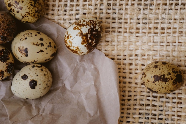 Easter quail eggs on craft paper and rustic burlap background Vintage photo processing