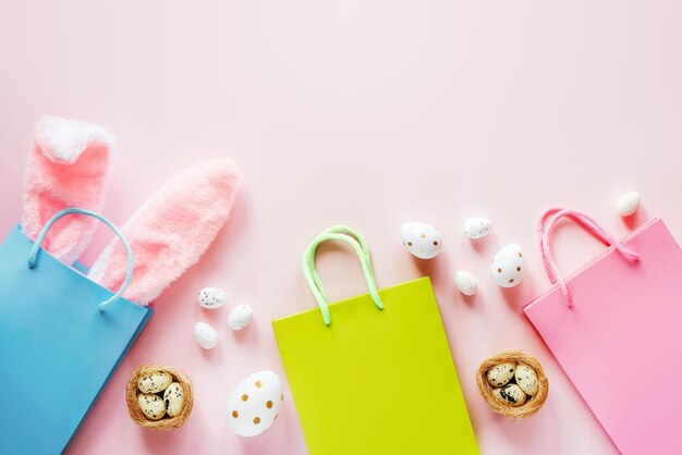 Easter shopping background with green and pink shopping bags with easter bunny ears and easter eggs ...