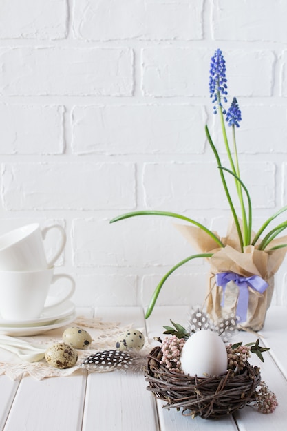 Easter spring decorative composition  with white chicken egg in a nest with flowers. Holiday decorations. Easter  festive table setting