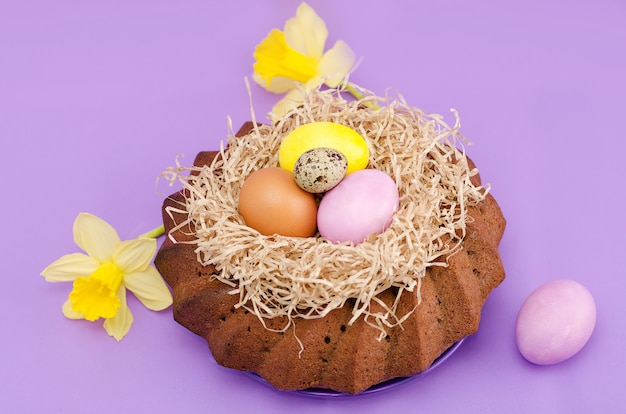 Easter still life, Easter cake, chicken and quail eggs, on a violet  background.