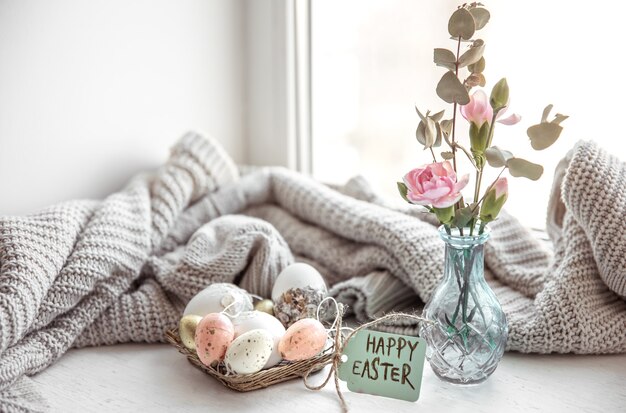 Easter still life with Easter eggs, fresh flowers in a vase and the inscription Happy Easter on the postcard.