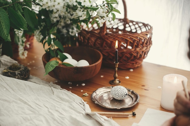 Easter Stylish Rural still life Stylish Easter egg with modern wax ornaments and natural dyed eggs on rustic wooden table with spring flowers basket candle linen cloth Zero waste