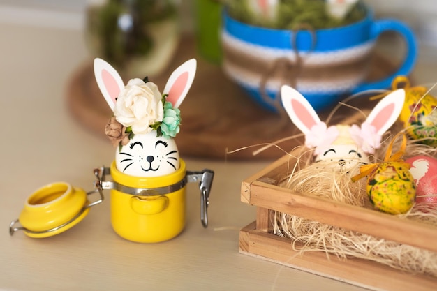 Пасхальные сладости и украшения яйца с забавными кроличьими ушами на кухонном домашнем столе