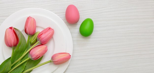 Easter table decoration egg pastel color in a plate and pink
tulip on white wood overhead