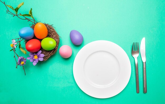 Easter table place setting easter eggs empty white plate green background