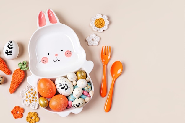 Easter table setting decoration with cute plate in the shape of a bunny with Easter eggs candy carrot and flowers Happy Easter concept Idea for Easter dinner