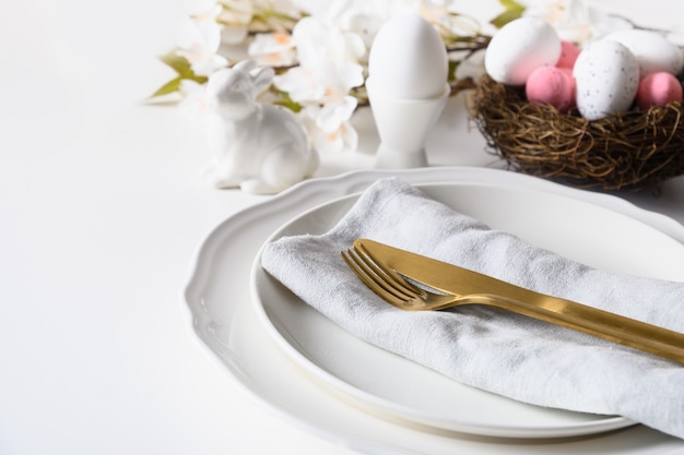 Easter table setting with blooming flowers on white table.