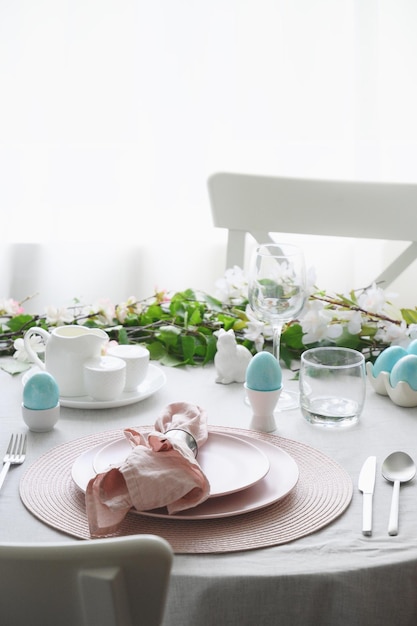 Easter table setting with blue coloful eggs festive decorations fresh flowers