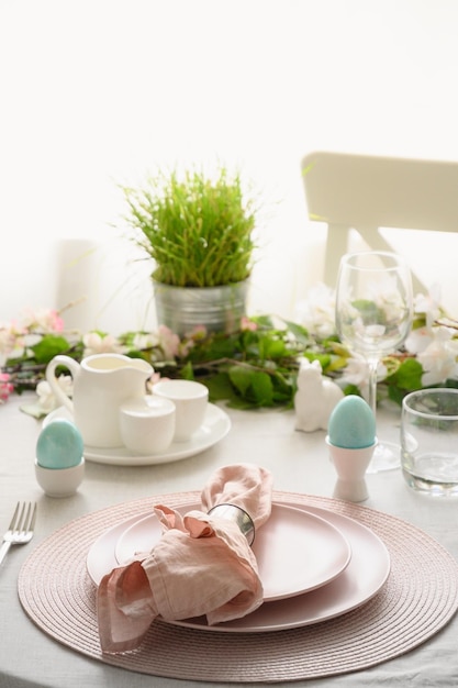 Easter table setting with blue coloful eggs festive decorations fresh flowers