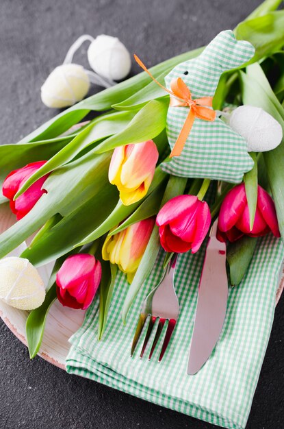 Easter table setting with bouquet of tulips and cutlery.