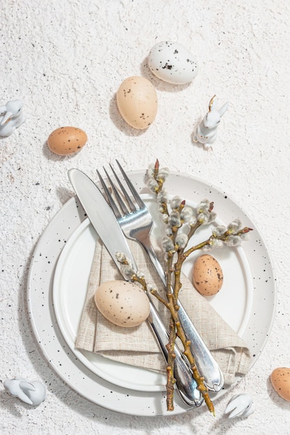 Easter table setting with eggs rabbits and willow Traditional festive symbols greeting card flat lay Trendy hard light dark shadow plaster background top view