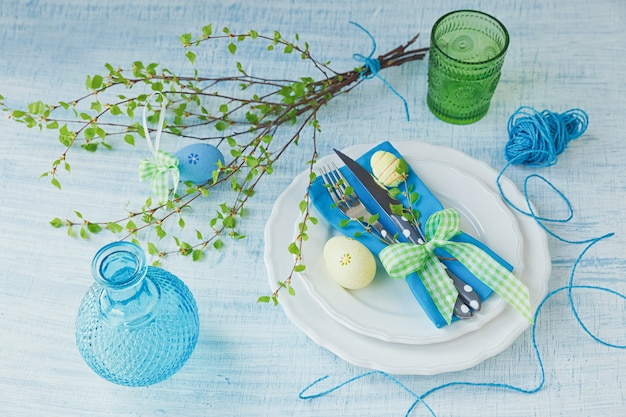 Easter table setting with painted eggs and cutlery a blue wooden background