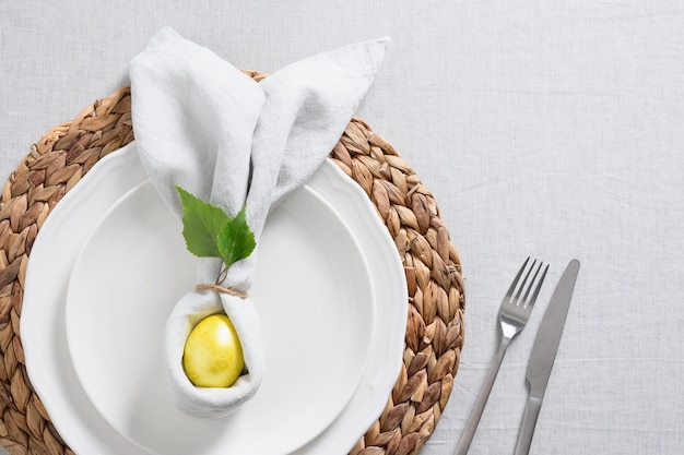 Easter table setting with yellow chick eggs fresh flowers on gray linen tablecloth