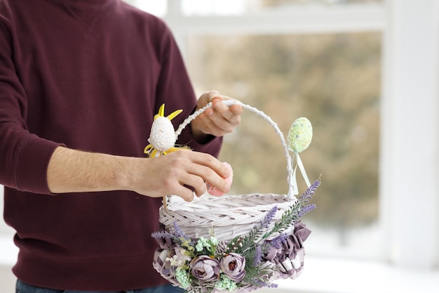 Foto giocattoli di pasqua cesto di pasqua con un coniglio decorativo nelle mani di un uomo spazio di copia dello sfondo sfocato