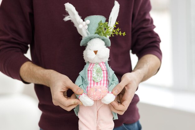 Photo easter toys easter basket with a decorative rabbit in the hands of a man blurred background copy space