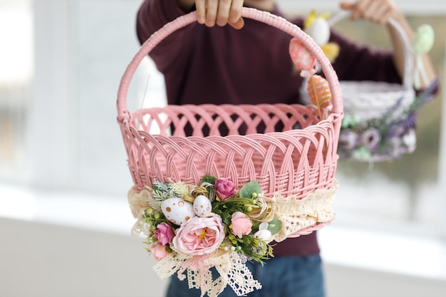 Photo easter toys easter basket with a decorative rabbit in the hands of a man blurred background copy space