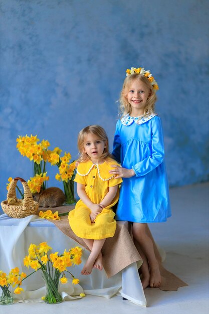 Easter traditions 2 beautiful girls in bright dresses hold rabbits and chickens in their hands easter card