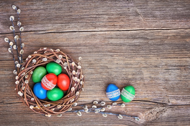 Easter willow wreath and colorful Easter eggs on old wooden wall. Top view