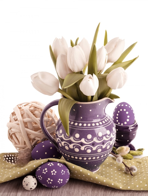 Foto pasqua con tulipani bianchi in brocca viola e corrispondenti uova di pasqua