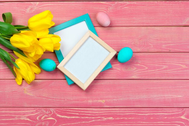 Easter . Wooden frame with easter eggs and tulips on colorful 