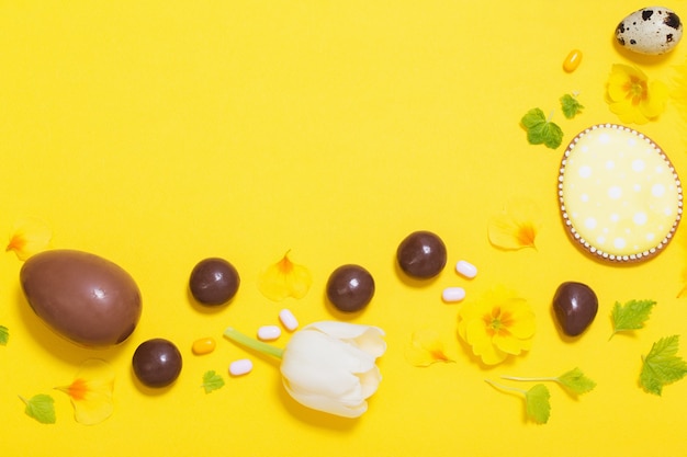 Easter yellow background with chocolatte eggs,    candy and spri