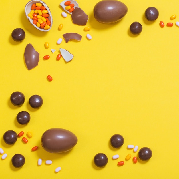ショコラの卵とキャンディーとイースター黄色の背景