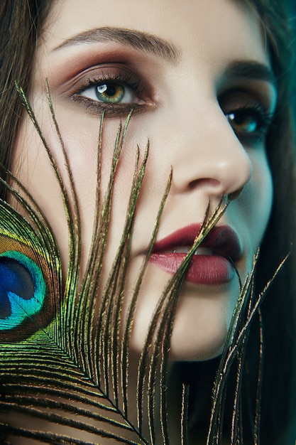 Photo eastern arab woman with a peacock feather on face