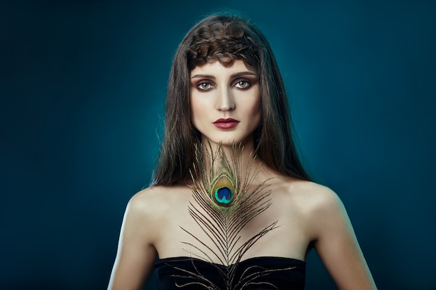 Eastern Arab woman with a peacock feather in her hands near her face. Beauty fashion makeup Arab women, big beautiful eyes. Beautiful smooth skin, peacock feather near eyes