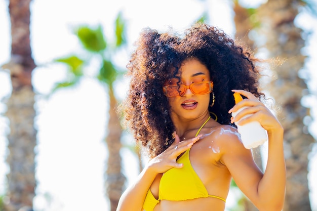 Eastern oriental ethnic woman with long curls holding bottle cream from sun rays