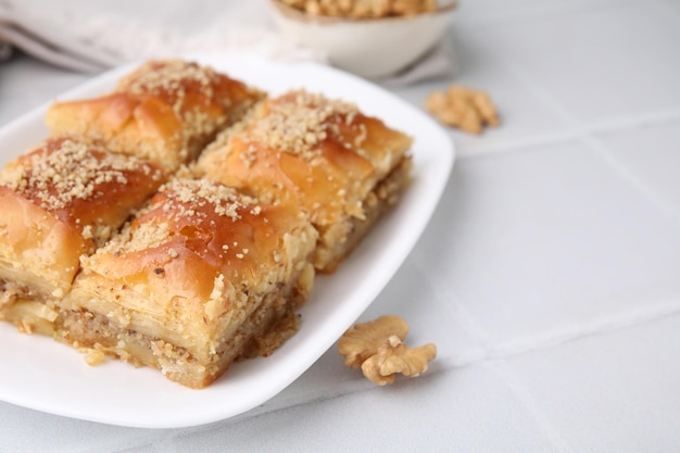 Восточные сладости Кусочки вкусной баклавы на белом плиточном столе вблизи Место для текста