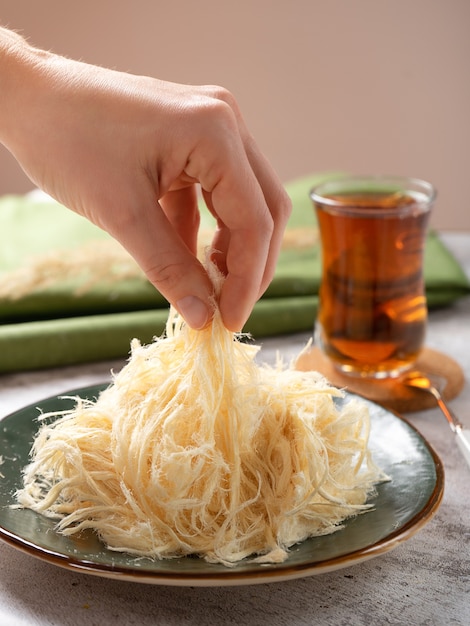 Eastern sweets - soft pashmak halva on a platter, in the form of round lumps, with a cup of Turkish tea.