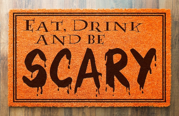 Eat Drink and Be Scary Halloween Orange Welcome Mat On Wood Floor Background