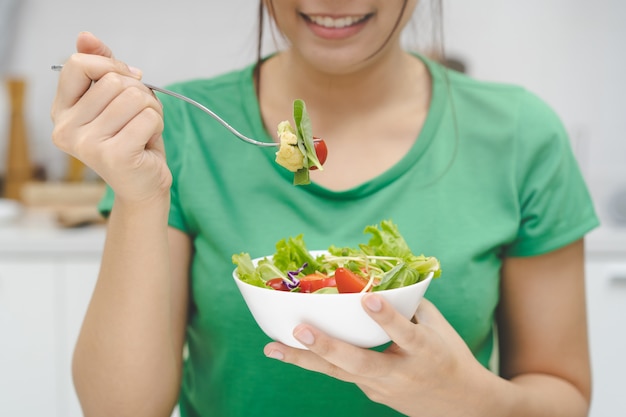 写真 健康のために緑を食べる。若い女の子は菜食主義者を食べることを楽しんでいます。