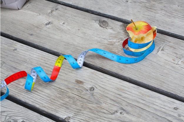 An eaten apple and a measuring band on an old wooden surface