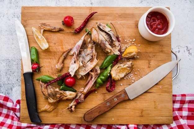 Eaten chicken wings and knife on wooden chopping board with ingredients