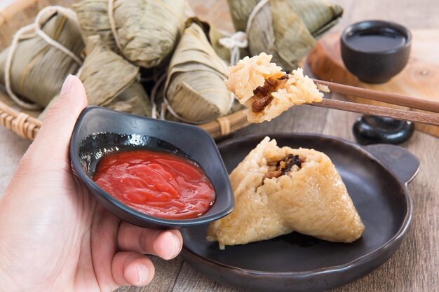 Еда китайских традиционных рисовых клецок цзунцзы на фестивале лодок-драконов