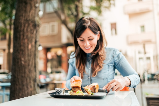 Eating delicious burger. Focus on the foreground, on the burger.