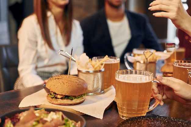 Eating and drinking Group of young friends sitting together in bar with beer