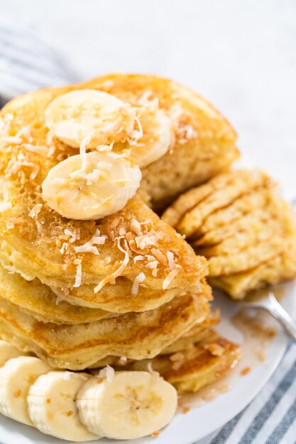 Eating freshly baked coconut banana pancakes garnished with sliced bananas and toasted coconut