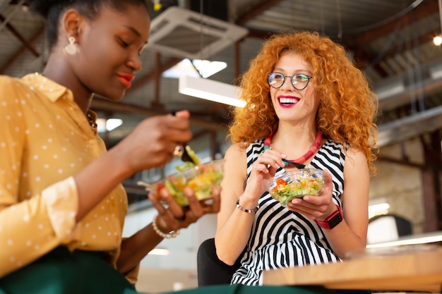 一緒に昼食を食べる。オフィスで一緒に昼食を食べている格好良いファッショナブルなサラリーマン