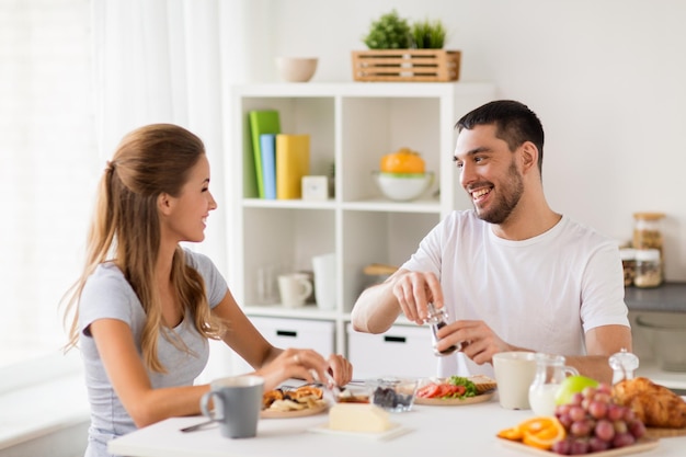 eating and people concept happy couple having breakfast at home