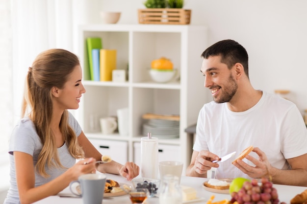 eating and people concept happy couple having breakfast at home