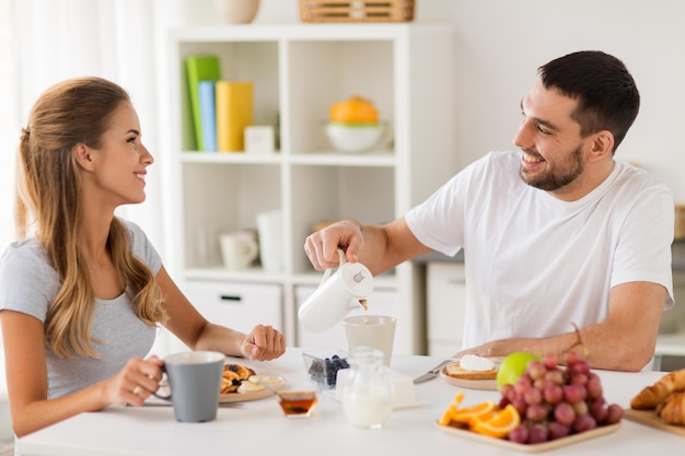 eating and people concept happy couple having breakfast at home