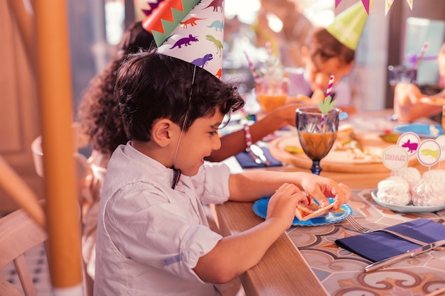 ピザを食べる。ピザを食べて、それを見ながら笑っている陽気な空腹の少年