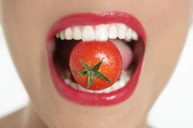 Photo eating a red tomato macro of woman mouth