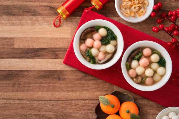 Photo eating red and white small tangyuan with savory soup and vegetable for lunar new year festival