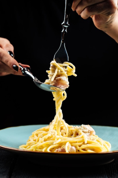Eating spaghetti carbonara with fork and spoon