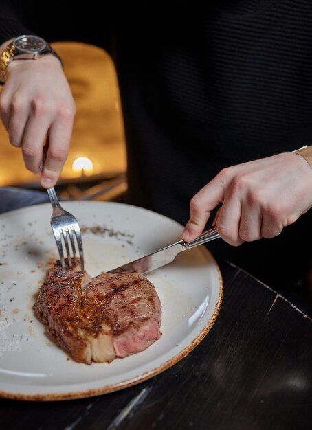 フォークとナイフマンの手でプレートから杭を食べる