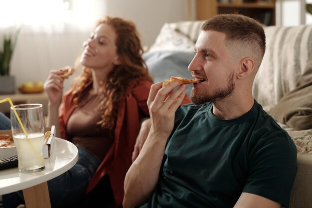 eating takeout pizza in front of tv set